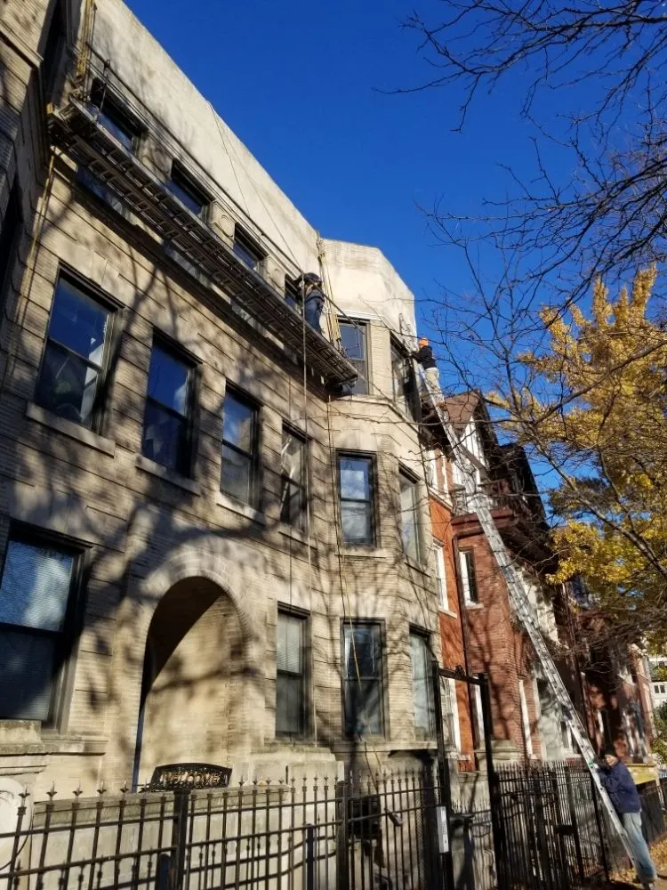 Multi-story Chicago greystone building with scaffolding against a blue sky